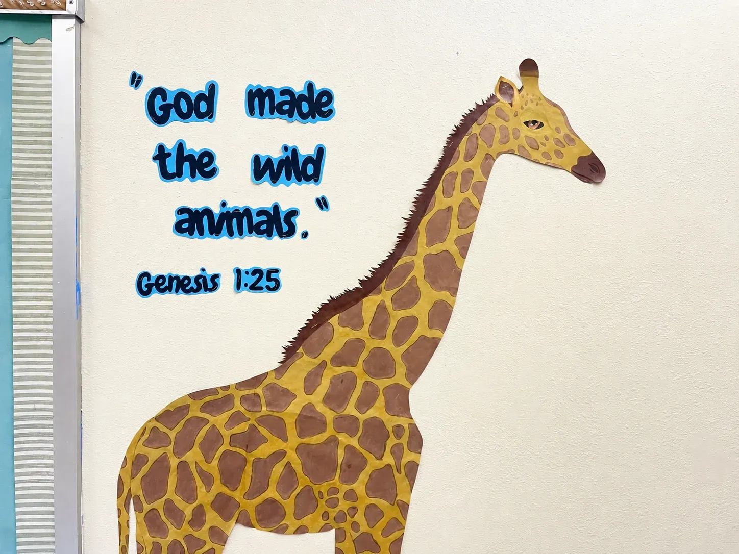 A hand-painted giraffe mural with the verse “God made the wild animals,” Genesis 1:25