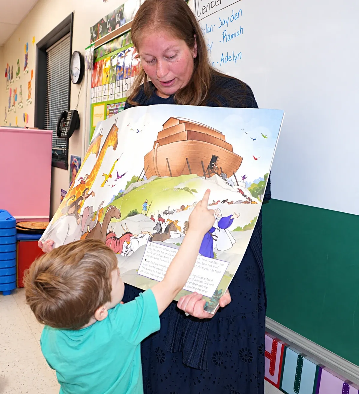 A teacher shows a Noah's Ark storybook to a preschooler during chapel time
