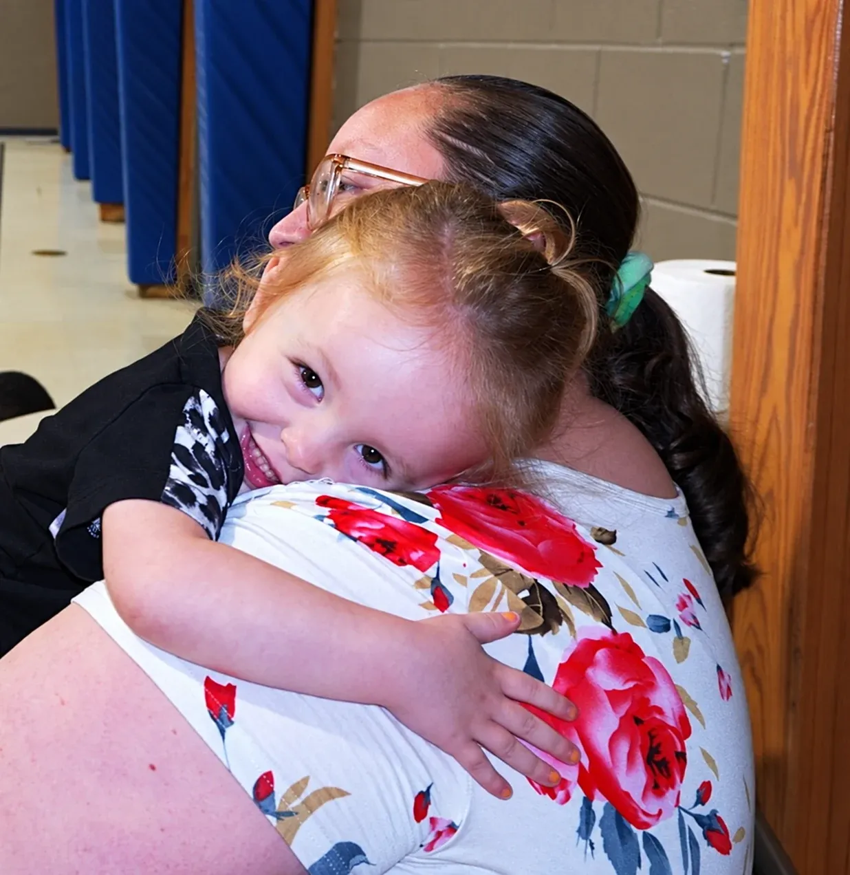 A teacher hugs a smiling toddler